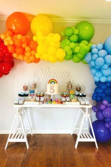 a rainbow birthday party with balloons and cupcakes to denote rainbow theme for kids birthday parties.